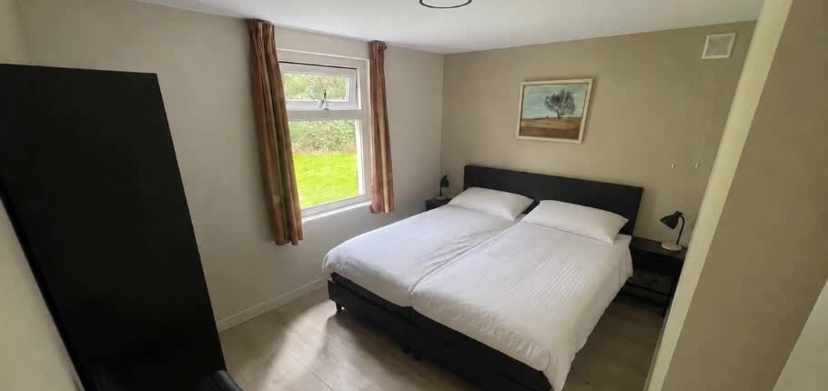 Opgemaakt tweepersoonsbed in een slaapkamer beneden